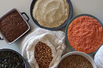 Bowls and bags full of various healthy grains and legumes. Top view.