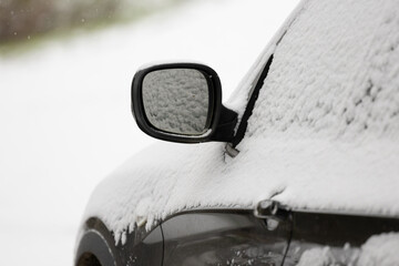 eine Detailaufnahme eines Autos, Autot&uuml;r, Au&szlig;enspiegel im Winter, eingeschneit es liegt Schnee