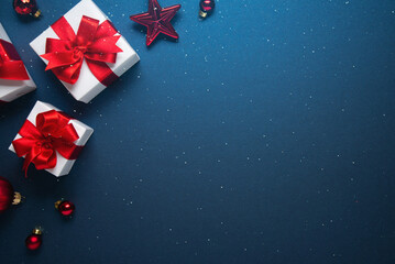 Merry Christmas and Happy Holidays greeting card, frame, banner. New Year. Red and white Christmas decorations and gifts on blue background top view. Winter xmas holiday celebration theme.