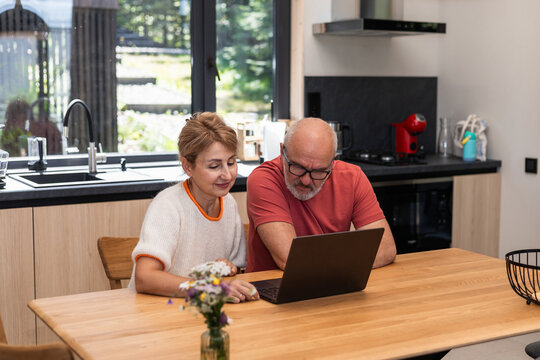 Couple using a laptop in a modern kitchen