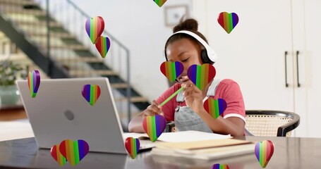 rainbow heart overlays floating initiating schoolgirl tapping pencil, writing notes in online study - Powered by Adobe