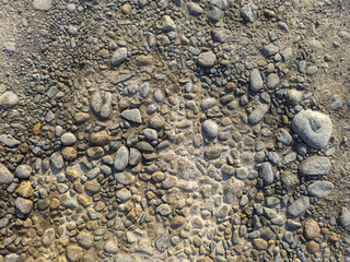 Numerous rocks of different sizes and colors scattered across dry ground. The rough textures and earthy tones create a natural and rugged atmosphere during daytime.