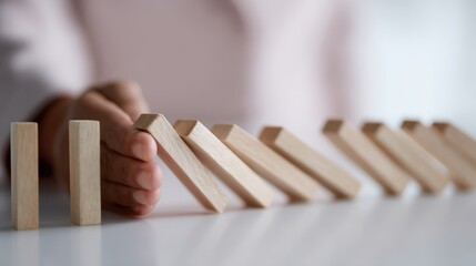 Businesswoman stopping a chain reaction of wooden dominoes, representing crisis management and business decision-making