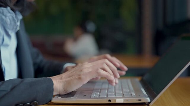 Professional female lawyer typing legal case on laptop in law office, focus on hands and technology.