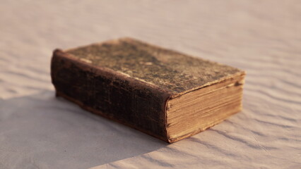 A vintage leather bound book lies on gentle fabric, illuminated by soft sunlight. The rich texture invites curiosity and exploration of its timeless stories and wisdom from the past.