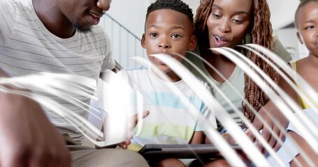 Father leaning and guiding son as tapping tablet making swirling tech data streams around family - Powered by Adobe