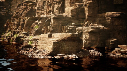Sunlight glimmers on calm water reflecting rugged cliffs. The natural beauty shows layers of stone with vibrant greenery, creating a serene escape in the great outdoors.