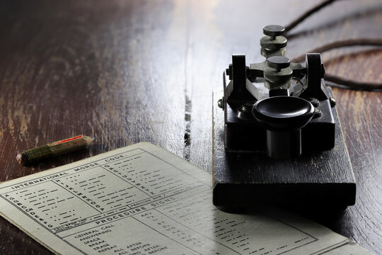 morse key with morse code chart on desk