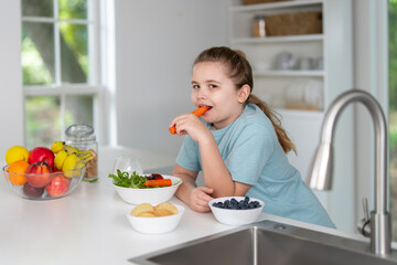 Kids eating healthy food in modern kitchen. Happy kids enjoying fresh vegetables for dinner in modern kitchen. Cute kids eating vegetarian dinner in modern kitchen. Modern kitchen for children.