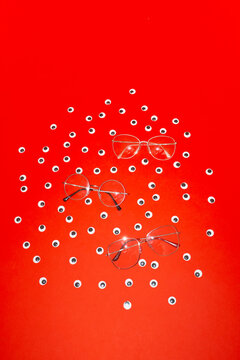 Conceptual image of glasses and eyes on red background