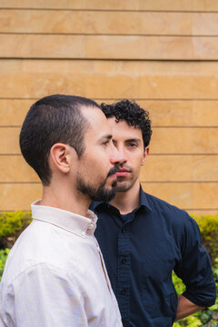 Two young adult twin brothers posing against a wall outdoors, expressing family connection