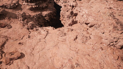The scene captures a vast, arid desert with intricate rock formations. As the sun sets, shadows deepen, revealing the rugged beauty of nature. Dry earth and cracks are prominent.