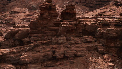 Unique rock structures rise from the dry ground, showcasing intricate shapes and textures. The sun casts shadows, highlighting the beauty of this desolate yet captivating environment.