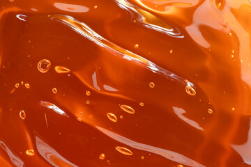 Vibrant orange cosmetic gel with bubbles and shine