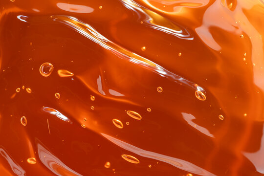 Vibrant orange cosmetic gel with bubbles and shine