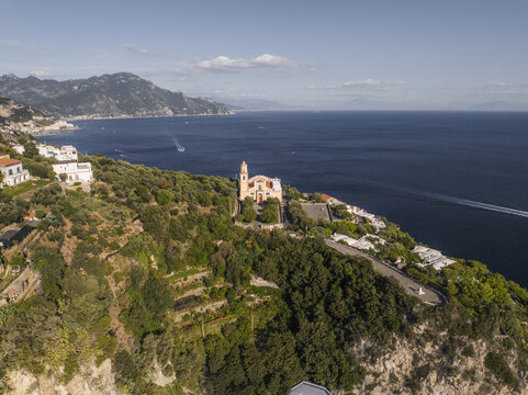 Aerial view of the vibrant Santa Maria de Gradillo church perched on a cliffside overlooking the deep blue sea, Conca dei Marini, Amalfi Coast, Campania, Italy.