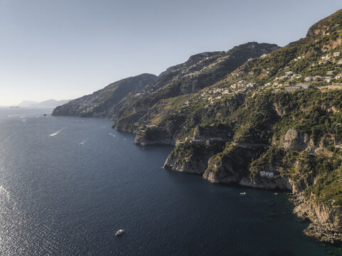 Aerial view of the Amalfi Coast's dramatic cliffs plunging into the Tyrrhenian Sea, dotted with bright white buildings and lush green vegetation., Conca dei Marini, Amalfi Coast, Campania, Italy.