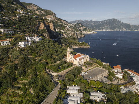 Aerial view of a church with an orange tiled roof standing prominently against the backdrop of the azure sea, Conca dei Marini, Amalfi Coast, Campania, Italy.
