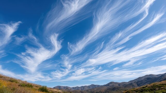 Vast Blue Sky with Wispy White Clouds Above Rolling Hills in a Scenic Landscape