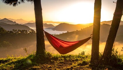 A red hammock is strung between three trees, overlooking a misty mountain range at sunrise, creating a serene and scenic landscape