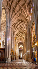 Fototapeta premium The Segovia Cathedral interior showcases towering Gothic arches and an ornate vaulted ceiling. Massive columns frame the central altarpiece and detailed stained glass
