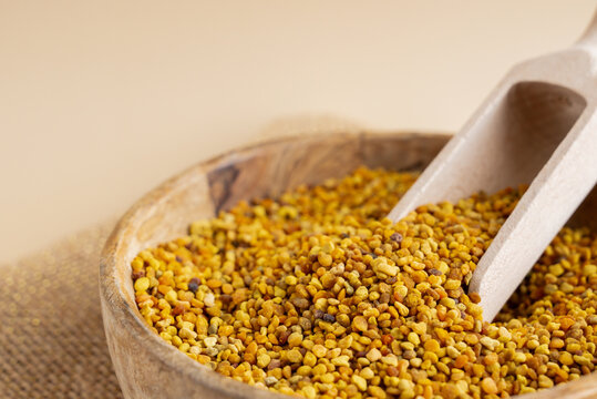Natural bee pollen in wooden bowl with beige background