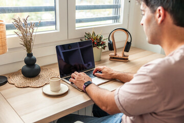 Young Hispanic man teleworking from home using laptop