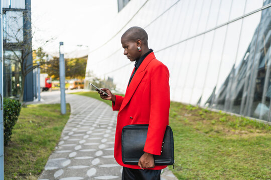 Young man in bright attire checking his phone outdoors