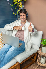 Smiling Hispanic man teleworking from home giving thumbs up