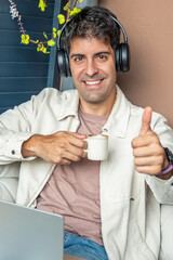 vertical Smiling Hispanic man teleworking from home giving thumbs up