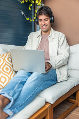 vertical Smiling Hispanic man working from home using laptop