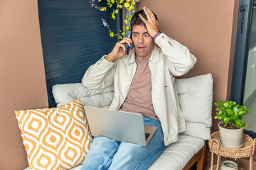Young man distressed receiving bad news teleworking from home