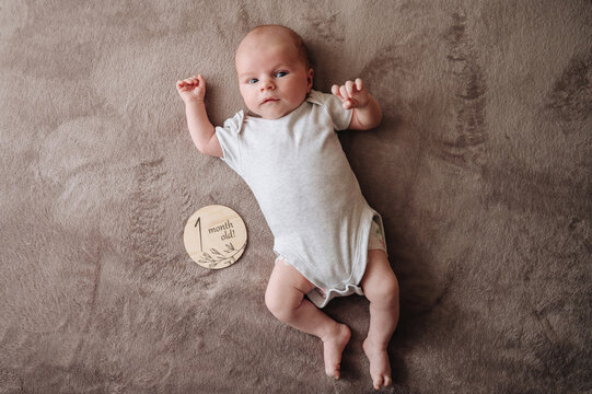 One month old baby lying on a soft brown blanket