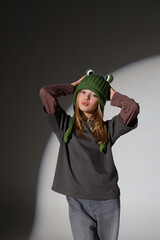 Caucasian female teen in frog hat and casual outfit posing confidently