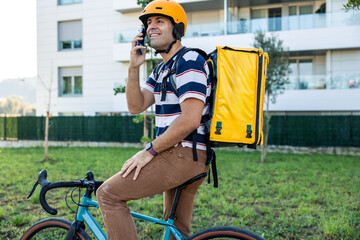 Hispanic delivery man talking on phone with bicycle