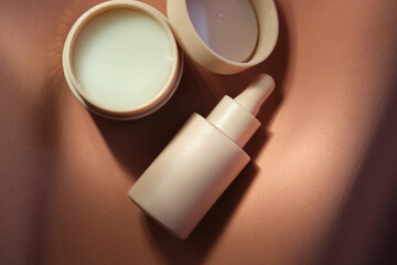 Face cream and serum on a soft beige background.