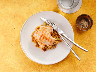 Delicious chicken breasts rest on a bed of colorful vegetable ragout, ready to be enjoyed with a fork and knife. A small bowl of spices adds to the meal's appeal