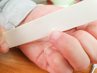 Nail file. A woman files and trims her fingernails. Manicure procedure, cosmetic care.