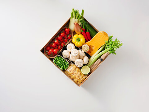 Naklejki Fresh vegetables including tomatoes, bell peppers, and green onions are neatly arranged in a wooden box. This lively display invites cooking creativity