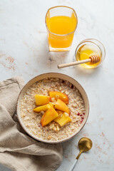 Oatmeal with peaches and nuts  in a bowl on a marble background with honey