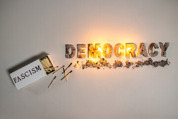 The word democracy burns against white seamless background