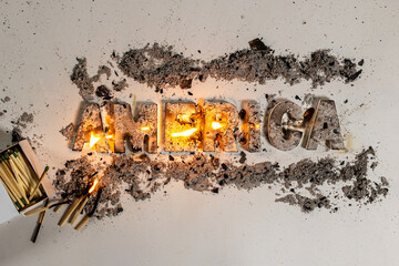 The word America lies charred and flaming against white seamless