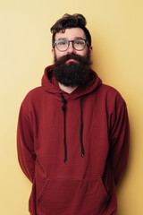 Obraz premium Man in Red Hoodie Smiling Against Pale Yellow Background