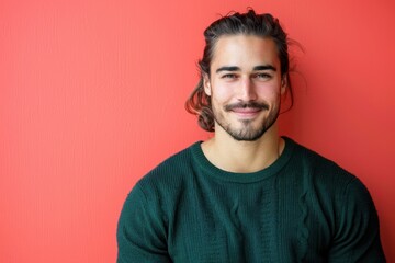 Obraz premium Man with Ponytail in Green Sweater Against Coral Background Smiling