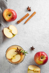 Apple cider with cinnamon, anise, and rosemary in glass on a light background with fresh fruits