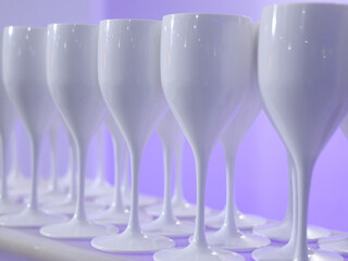 Row of white glasses. stock A row of perfectly aligned white glasses creates a harmonious and modern visual effect. The glossy surfaces reflect the soft light, giving the scene a clean, sophisticated,