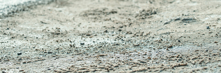 Rough muddy surface with textured dirt and rocks under daylight.