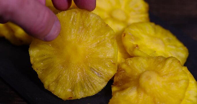 dried ripe bright yellow pineapple on a black slate board, cut into rings and dried yellow clean slices of ripe pineapple for long-term storage and used as a sweet