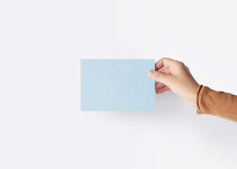 Hand holding a blank light blue card on a white background