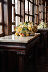 Elegant floral arrangement of pink roses, white blooms, and foliage in a silver vase, placed on a marble table in soft natural light.